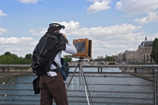 photographer with old plate camera on the seine bridge Passerelle Solferino in Paris