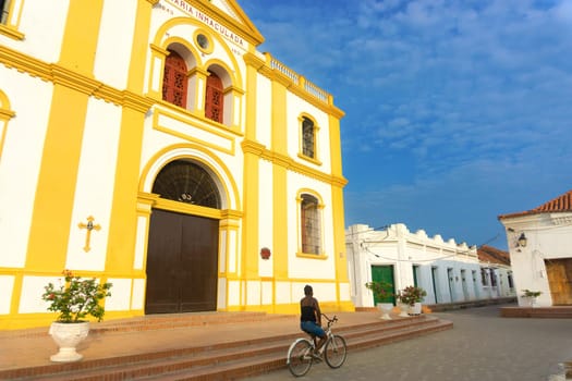 MOMPOX, COLOMBIA - MAY 28: Woman rides a bicycle past the cathedral in Mompox, Colombia  on May 28, 2016