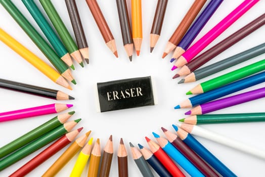 Circle made of colouring pencils with eraser in middle isolated on white background,education concept image with copy space available
