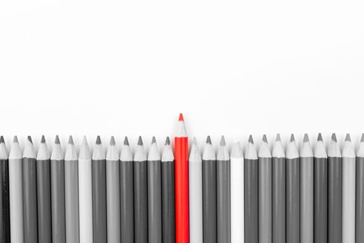Red pencil standing out from monochrome pencils crowd, copy space available. Stand out from the crowd concept