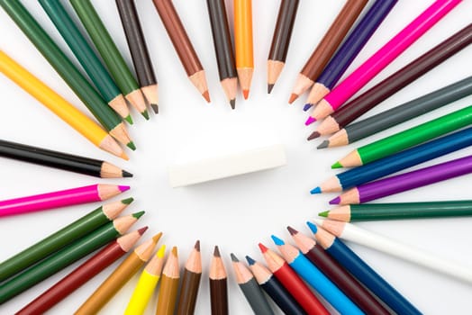 Circle made of colouring pencils with eraser in middle isolated on white background,education concept image with copy space available