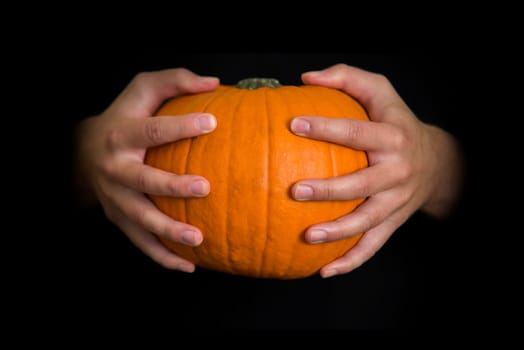 hands holding a halloween pumpkin,with copy space on black