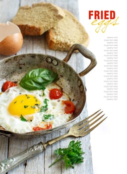 Fried egg with tomatoes, homemade bread and herbs on a old frying pan on wood