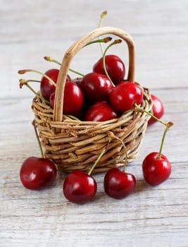 Red cherries in a basket on a wooden background
