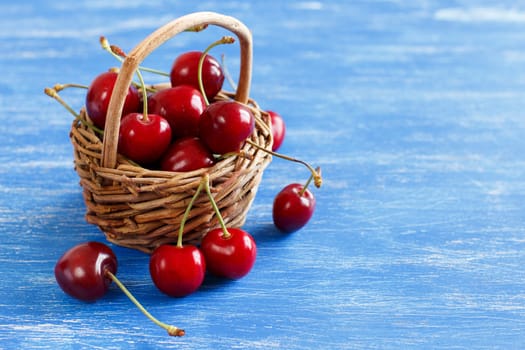 Red cherries in a basket on a blue background