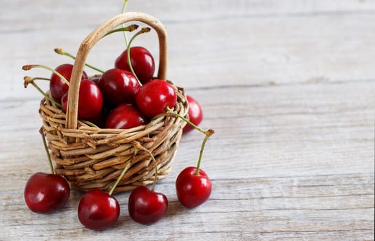 Red cherries in a basket on a wooden background