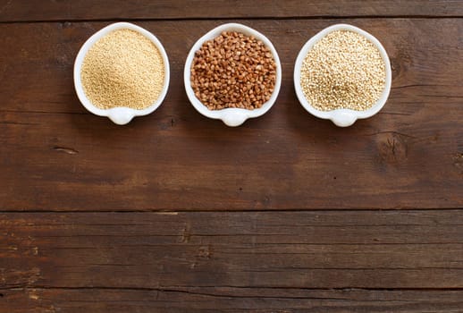 Amaranth, buckwheat and quinoa in bowls on a wooden table