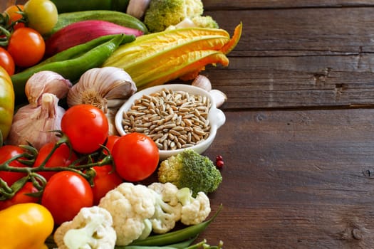 Raw Rye Grain in a bowl and vegetables on wood