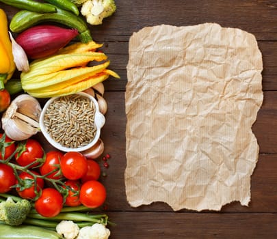 Raw Rye Grain in a bowl and vegetables with craft paper on wooden table