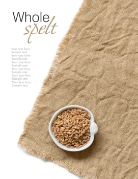 Whole unpolished spelt in a bowl on burlap