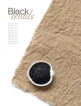 Black Lentils on a bowl on burlap top view