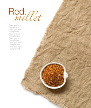 Raw brown millet in a bowl on burlap and wood