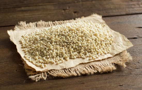 White sorghum grain on a wooden table close up