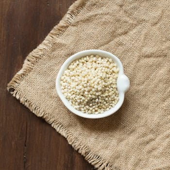White Sorghum grain in a bowl on burlap background