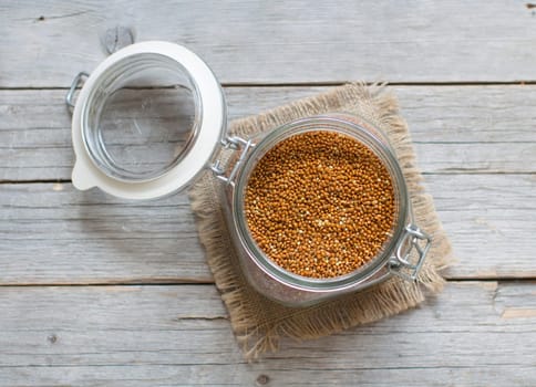Raw brown millet in a glass jar and wood