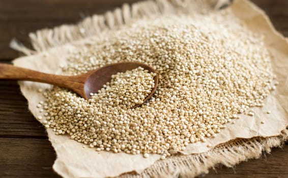 Pile of White Quinoa with a spoon on a wooden table