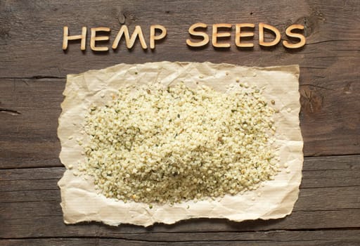Raw organic hemp seeds on a wooden table with wooden letters