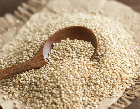 Pile of White Quinoa with a spoon on a wooden table