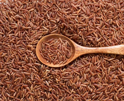 Red rice with a wooden spoon close up