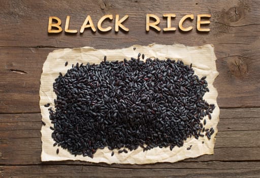 Black rice on a wooden table close up