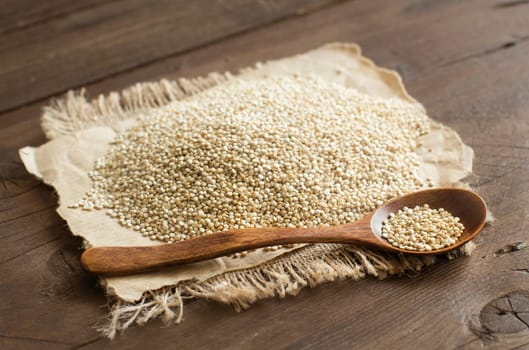 Pile of White Quinoa with a spoon on a wooden table