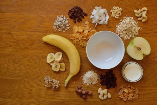 Muesli bowl on breakfast table with individual components of a muesli around it