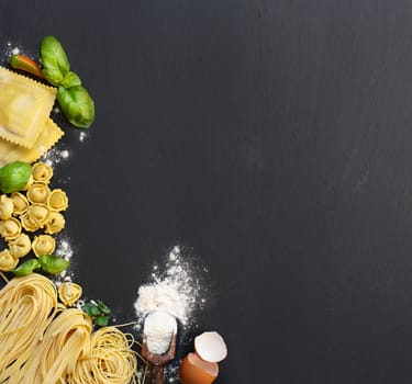 Fresh pasta and ingredients on a dark board