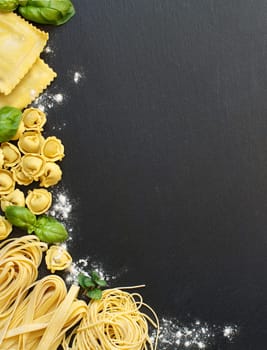 Homemade raw Italian pasta and basil on a dark background