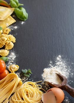 Fresh pasta and ingredients on a dark board top view