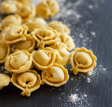 Homemade raw Italian tortellini on a dark background