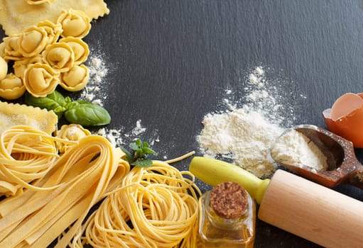 Fresh pasta and ingredients on a dark board close up