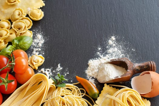 Fresh pasta and ingredients on a dark board