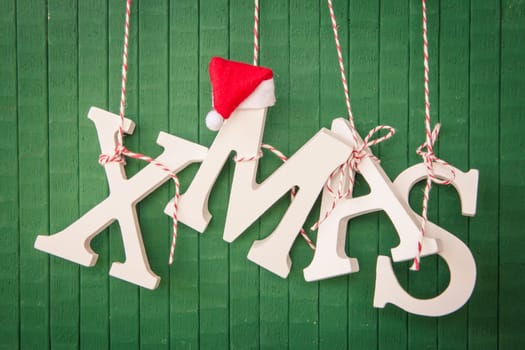 Xmas in wooden letters hanging on a green background of wood