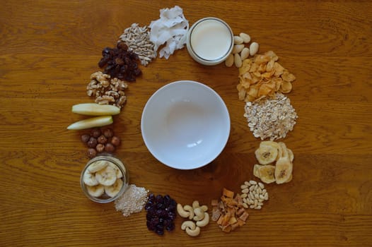 Muesli bowl on breakfast table with individual components of a muesli around it