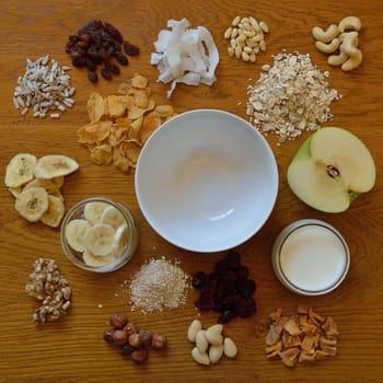 Muesli bowl on breakfast table with individual components of a muesli around it