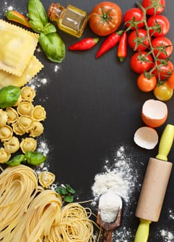 Fresh pasta and ingredients on a dark board top view
