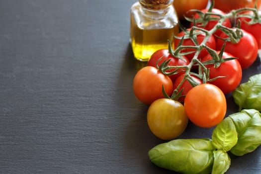 Cherry tomatoes, basil and olive oil on a dark background