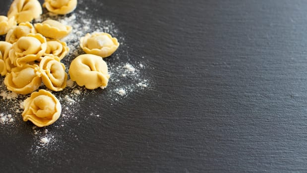 Homemade raw Italian tortellini on a dark background