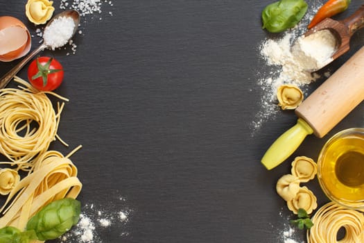 Fresh pasta and ingredients on a dark board top view
