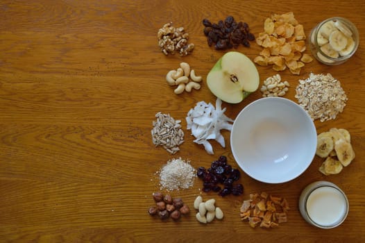 Muesli bowl on breakfast table with individual components of a muesli around it