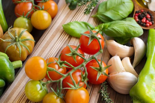 Raw fettuccine pasta, vegetables and herbs on wooden background