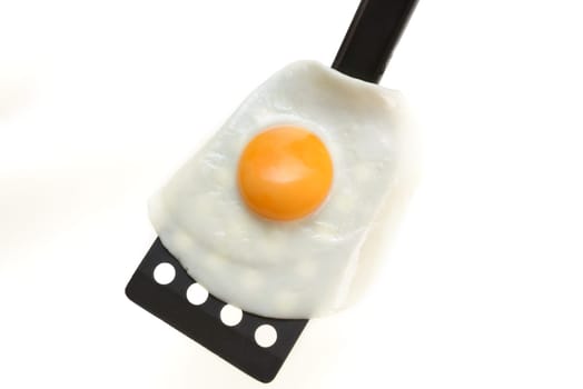 Fried egg on the spatula, ready to be served. White background.