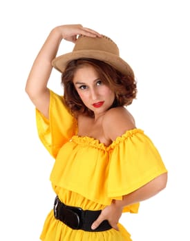 A beautiful young woman standing in a yellow blouse isolated for white.background holding a cowboy hat on her head..