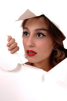 The face of a beautiful young woman showing trough a hole in the .paper, with big eyes, isolated for white background..