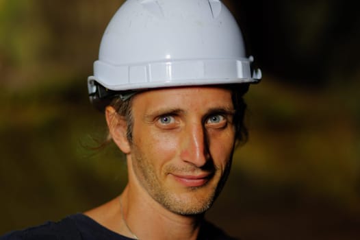 a portrait of a worker with white helmet on head, on nature background