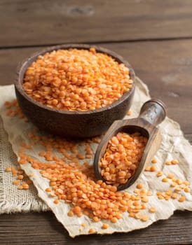 Red lentils in a bowl with a spoon on a wooden table