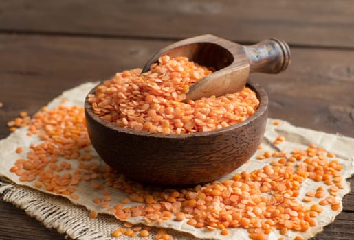 Red lentils in a bowl with a spoon on a wooden table