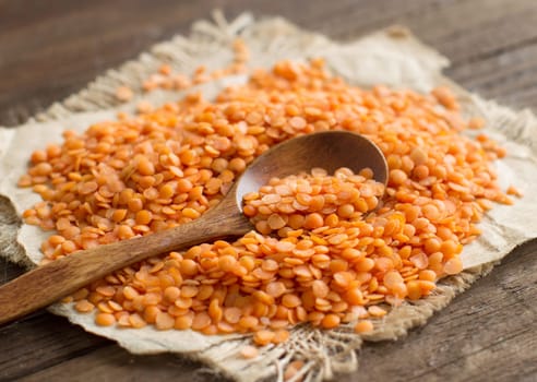 Red lentils with a spoon close up on wooden table