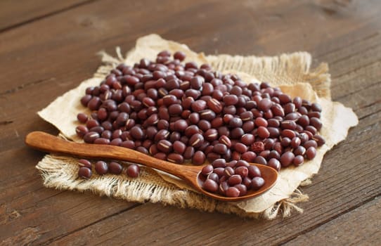 Raw azuki beans with a spoon on a wooden table