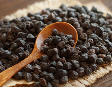 Black Chickpea with a spoon on a wooden table close up